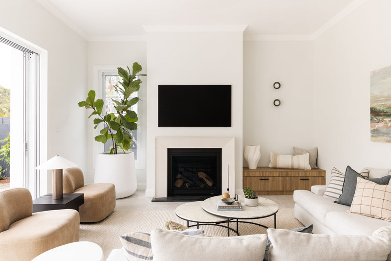 A bright, modern living room featuring designer furniture selections including modern occasional chairs, side tables and feature lighting, nested marble coffee table, floor rug and upholstered sofa. 
